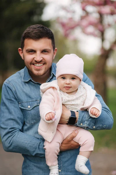 Mutlu genç baba küçük kızıyla yürüyor. Baba kucağına al küçük bebeği