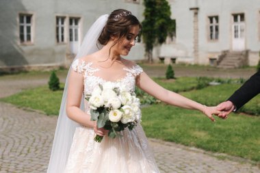 Yeni evliler büyük kalenin yanındaki parkta yürüyorlar. Yakışıklı damat ile güzel gelin