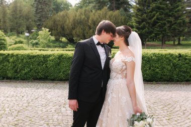 Yeni evliler büyük kalenin yanındaki parkta yürüyorlar. Yakışıklı damat ile güzel gelin