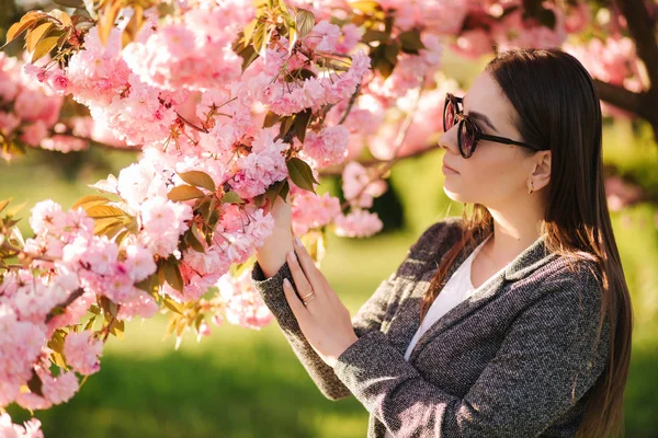 Retrato de una hermosa mujer en gafas de sol junto al árbol rosa — Foto de Stock