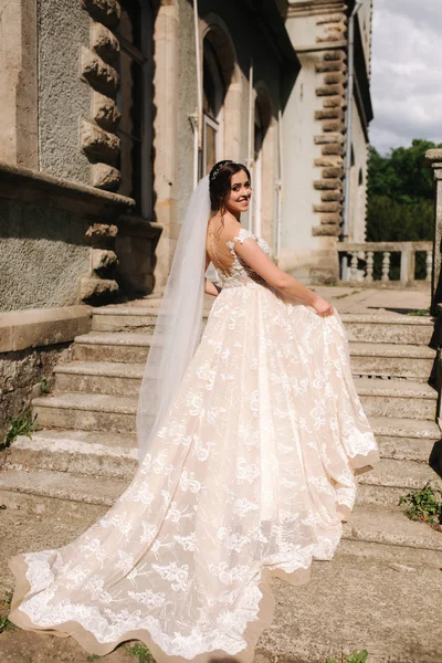 Hermosa novia en las escaleras por el castillo. vestido blanco — Foto de Stock