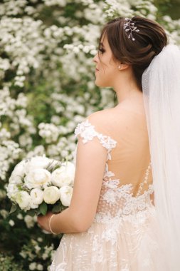 Muhteşem gelinlik Büyüleyici gelin tutun buket ve çiçek açan ağaçların önünde durmak