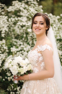 Muhteşem gelinlik Büyüleyici gelin tutun buket ve çiçek açan ağaçların önünde durmak