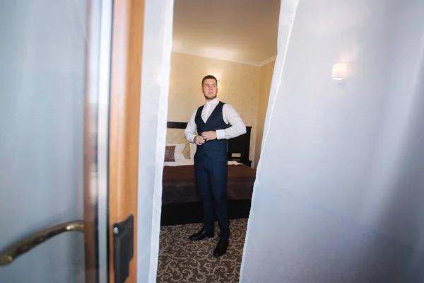 Knappe jonge bruidegom gekleed in het hotel. Ochtend in hotel — Stockfoto