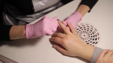 Profesyonel manikürcü tırnak derisini söker, tırnak derisini makasla keser. Güzellik salonunda profesyonel manikür videosu.