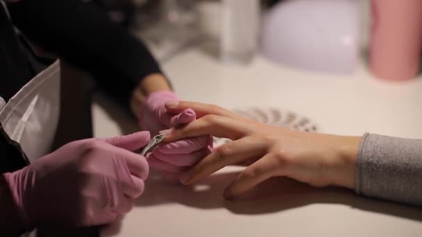 Професійний манікюрник видаляє суху шкіру кутикули біля нігтів, розрізаючи її ножицями. Крупним планом відео професійного манікюру в салоні краси — стокове відео
