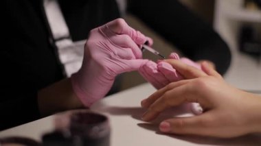 Manikür ustasına yakın plan, manikürcüye manikür yaptırıyor.
