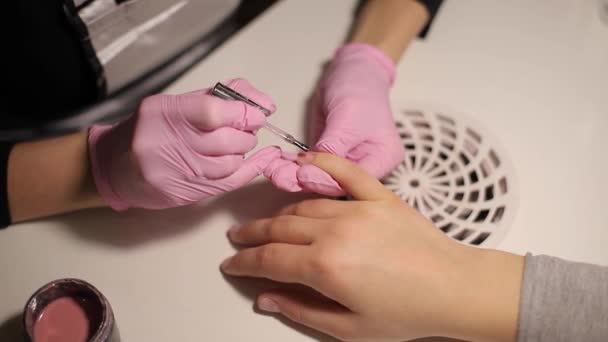 O close-up de mulheres pinta pregos. Arte de unhas de manicure. A fêmea trabalha com luvas cor de rosa. Fechar as mãos de mulheres — Vídeo de Stock