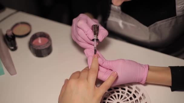 Detailní záběr žen maluje nehty. Umění manikúry. Žena pracuje v růžových rukavicích. Zblízka ženské ruce — Stock video