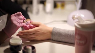 Manikür ustasına yakın plan, manikürcüye manikür yaptırıyor.