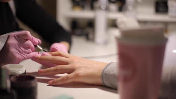Крупный план маникюра делает профессиональный маникюр женщине в салоне по уходу за ногтями — стоковое видео