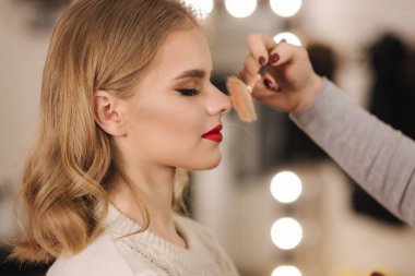 Makyöz güzellik stüdyosunda çalışıyor. Profesyonel makyaj ustası tarafından başvurulan kadın. Güzel makyöz, sarı saç modeline makyaj yapar.