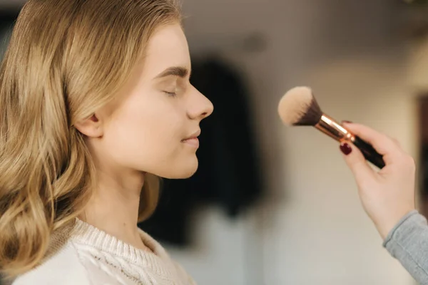 Makeup artist work in her beauty studio. Portrait of Woman applying by professional make up master. Beautiful make up artist start making a makeup for blond hair model — Stock Photo, Image