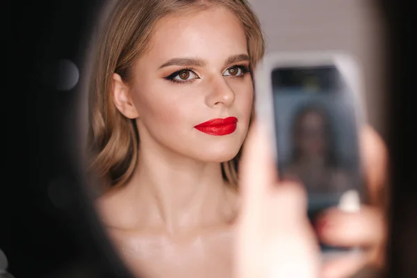 Portret pięknej blondynki po makijażu w studiu kosmetycznym. Czerwona szminka. Lampa pierścieniowa — Zdjęcie stockowe