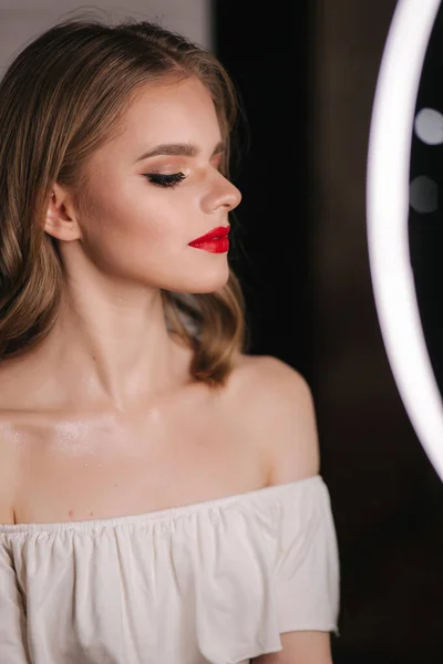 Portrait of beautiful blond hair lady after makeup in beauty studio. Red lipstick. Ring lamp