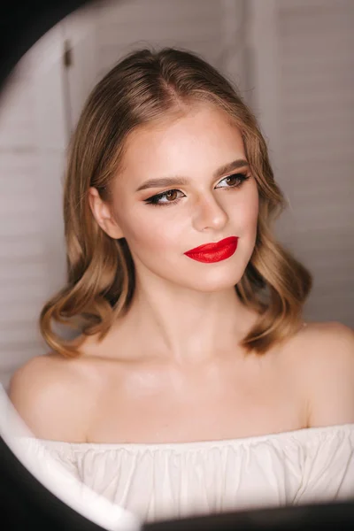 Portret pięknej blondynki po makijażu w studiu kosmetycznym. Czerwona szminka. Lampa pierścieniowa — Zdjęcie stockowe
