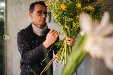 Çiçekçi bayram için buket yapar. Aile çiçek işi. Güzel bir çiçek kompozisyonu. Ayrıntılar. Kapat.