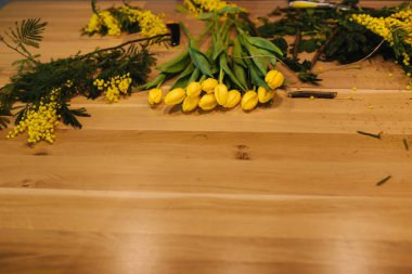 Çiçekçiliğin çalışma yeri. Ahşap masada sarı lale.