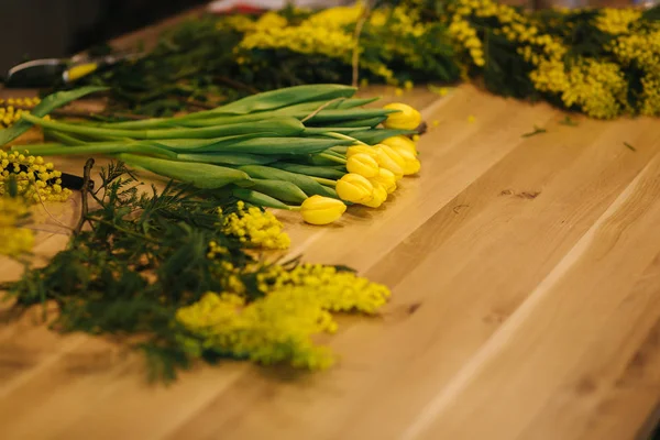 Lugar de trabajo de florística. Tulipanes amarillos lila sobre mesa de madera —  Fotos de Stock