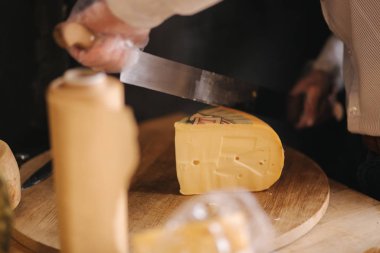 Tahtada peynir dilimleyen bir adam. Peynir dükkanı