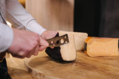 Zevk için peynir dilimleyen bir adam. Genç işçi peynir için özel bıçak kullanır.