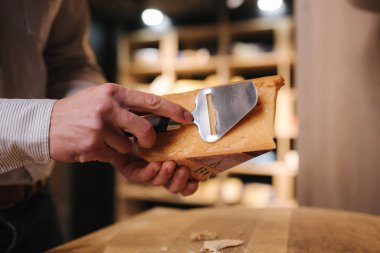 Zevk için peynir dilimleyen bir adam. Genç işçi peynir için özel bıçak kullanır.