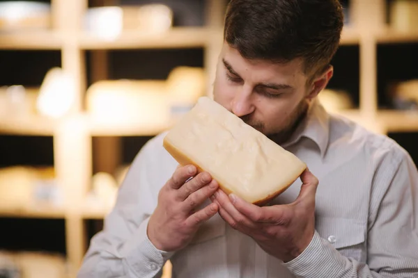 Portrait of Handsome bearded man sniff aged cheese in shop