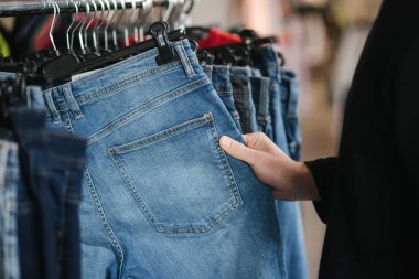 Kıyafet seçen yakışıklı müşterilere yaklaş. Kotları tutan adamın eli