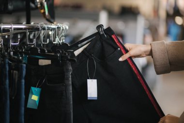 Kot pantolon seçen kadınlara yakın çekim. Elbise mağazasında kot tutan bir kadın eli.