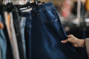 Kot pantolon seçen kadınlara yakın çekim. Elbise mağazasında kot tutan bir kadın eli.