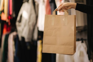 Giysi dükkanında el işi çantasıyla. Satın alınmış kadın el tepe çantası.