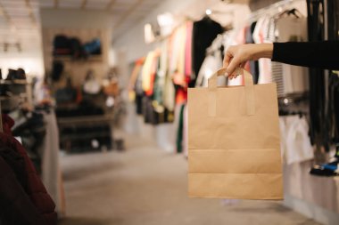 Giysi dükkanında el işi çantasıyla. Satın alınmış kadın el tepe çantası.