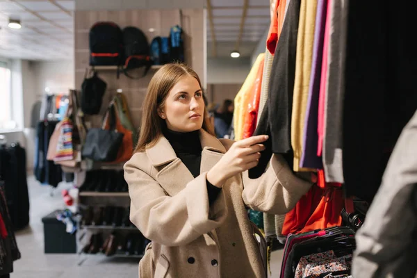 Young woman choosing clothes in clothes store — Stok fotoğraf