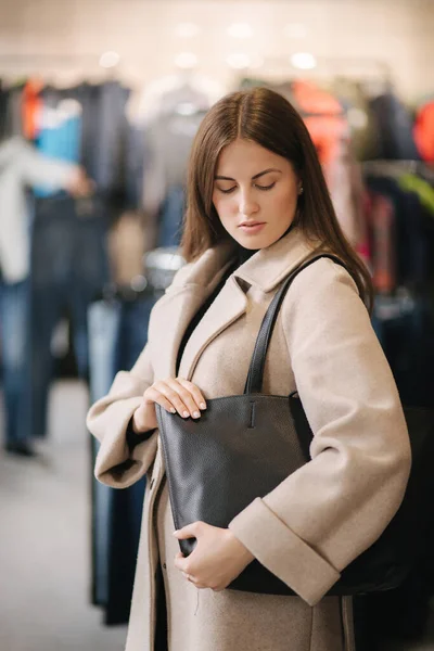 Mujer joven probándose la bolsa negra. Mujer en boutique — Foto de Stock