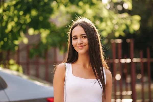 Atractiva joven mujer caminando en la ciudad en verano. Hermosa morena en camisa blanca. Sonríe —  Fotos de Stock