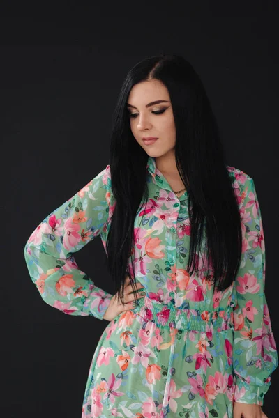 Young woman model demonstrating cloths on black background. Beautiful spring dress