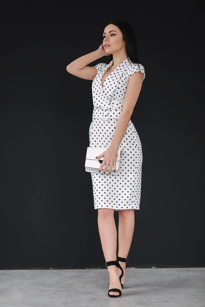 Krásný model demonstrující bílé jarní šaty. Mladá bruneta na černém pozadí — Stock fotografie