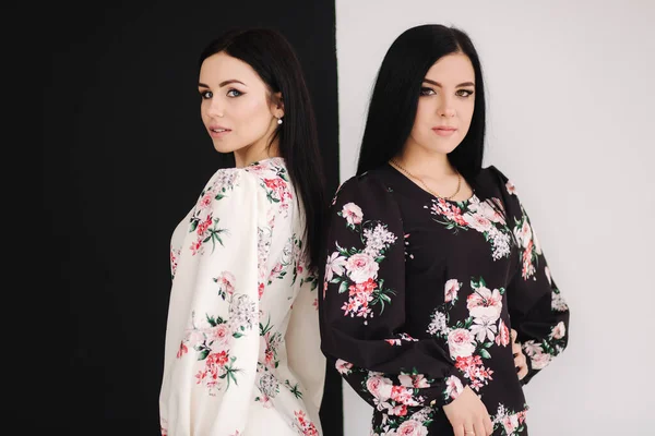 Dos modelos morenas de moda en vestidos de primavera posando en el estudio. Fondo blanco y negro — Foto de Stock