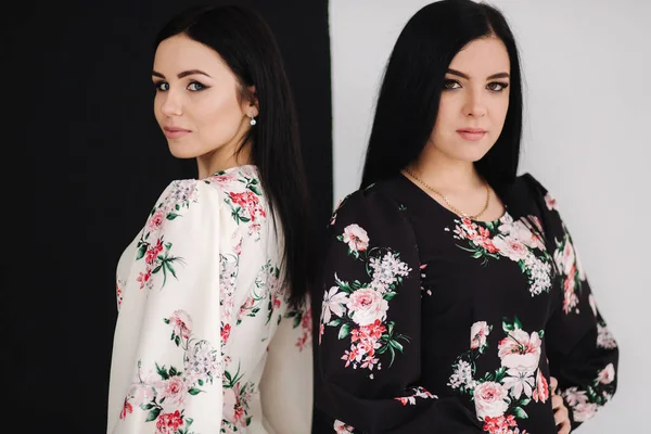 Dos modelos morenas de moda en vestidos de primavera posando en el estudio. Fondo blanco y negro — Foto de Stock