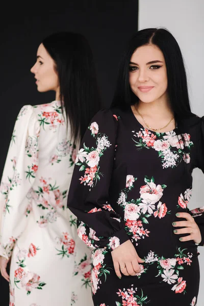 Två modebrunettmodeller i vårklänningar som poserar i ateljén. Svart och vit bakgrund — Stockfoto