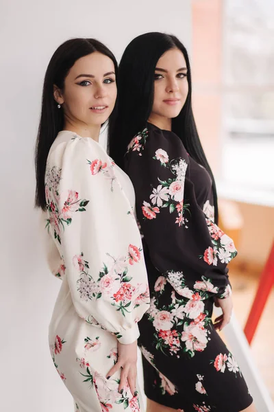 Zwei brünette Models in Frühlingskleidern posieren im Studio. Schwarz-weißer Hintergrund — Stockfoto