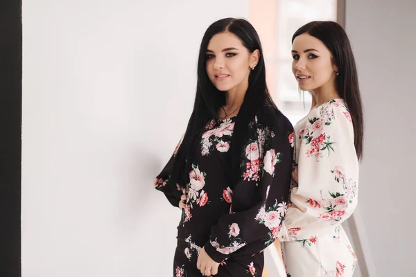 Zwei brünette Models in Frühlingskleidern posieren im Studio. Schwarz-weißer Hintergrund — Stockfoto