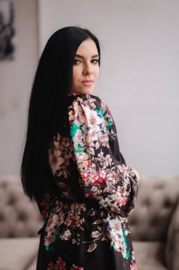 Stüdyoda bahar kıyafetlerini sergileyen güzel esmer kadın. Pencerenin yanında dur