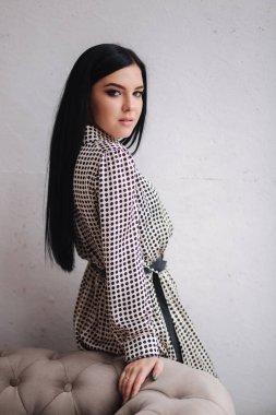 Kıyafetlerini gösteren çekici genç bir model. Zarif esmer kadın için bahar koleksiyonları. Güzel gri bahar elbisesi