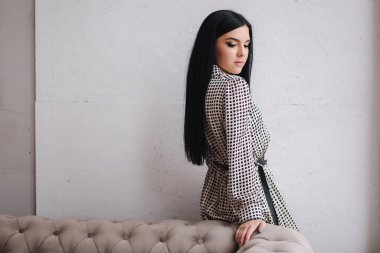 Kıyafetlerini gösteren çekici genç bir model. Zarif esmer kadın için bahar koleksiyonları. Güzel gri bahar elbisesi