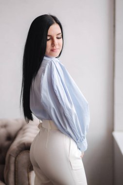 Kıyafetlerini gösteren çekici genç bir model. Zarif esmer kadın için bahar koleksiyonları. Mavi gömlek