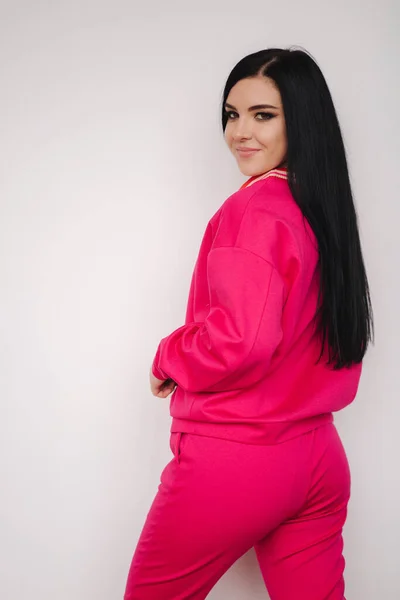 Attraente modello giovane in tuta rosa. Una donna che mostra vestiti in studio. Fondo bianco — Foto Stock