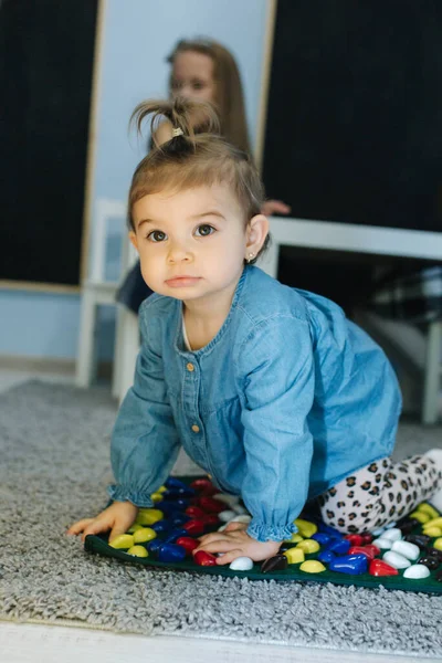 Малыш в детском саду играет. Девочка в синих джинсах. Милый малыш в детской. — стоковое фото
