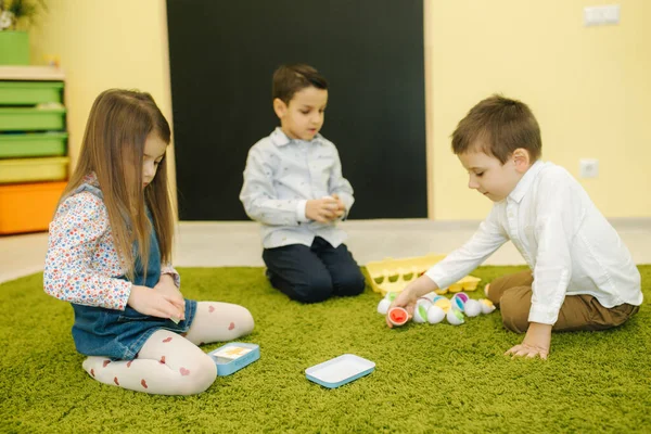 Dzieci bawią się jajkami w przedszkolu. Pokój dziecinny. Chłopiec i dziewczęta — Zdjęcie stockowe