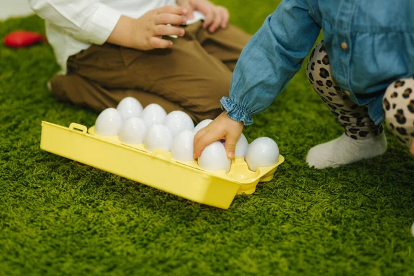 Los niños juegan con huevos de juguete en el jardín de infantes. Guardería. Niño y niñas — Foto de Stock